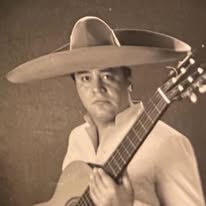 Roberto Acosta holding his guitar in mariachi attire